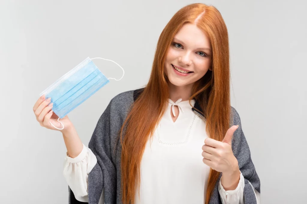 A woman who has mask in her hand and she is satisfy about cleaning service